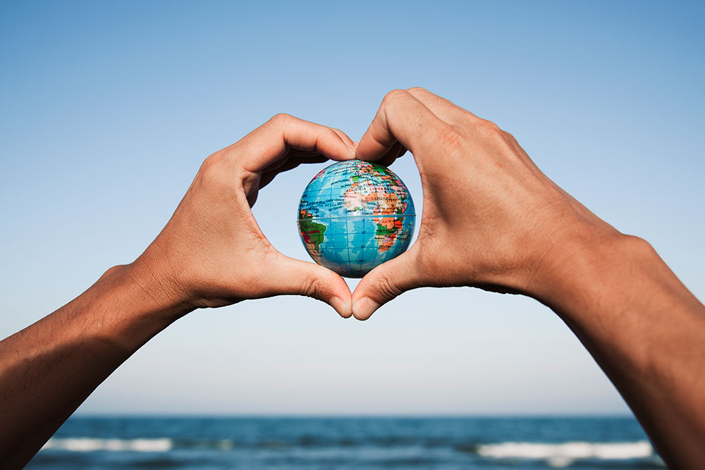 hands holding a miniature global in the shape of a heart