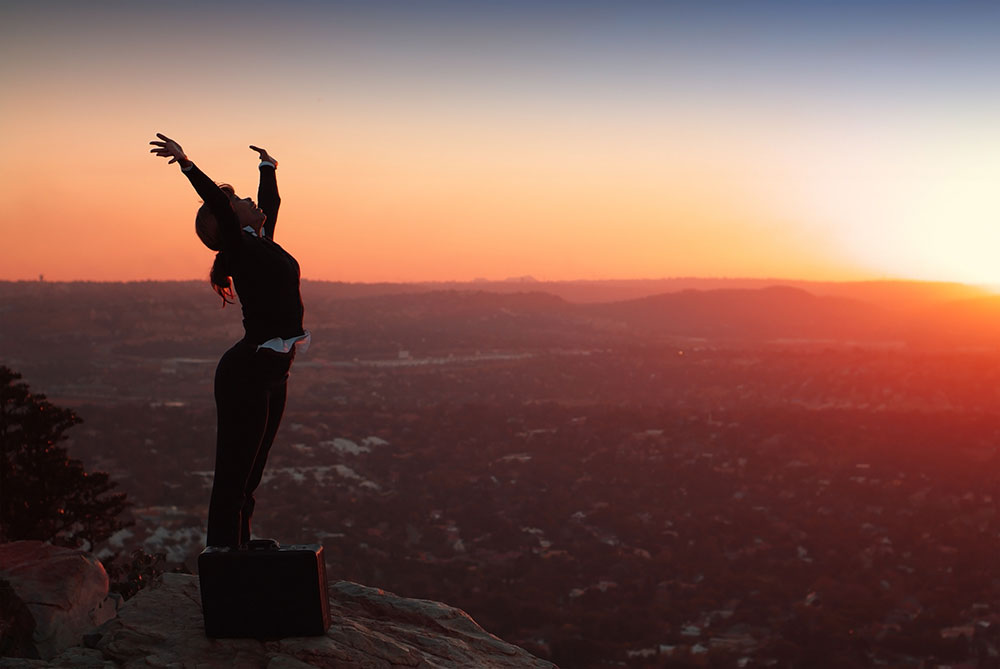 Happy businesswoman celebrating overlooking landscape sunset