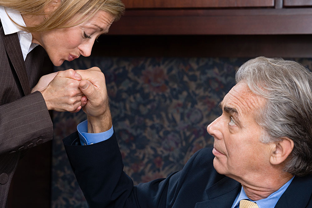 Business woman awkwardly kissing business man's hand