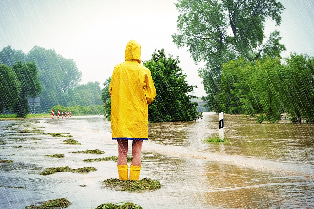 person in a raincoat standing in a flooded field