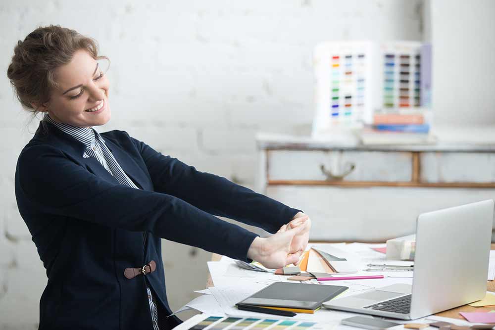 Young businesswoman stretching at her desk after a job well done