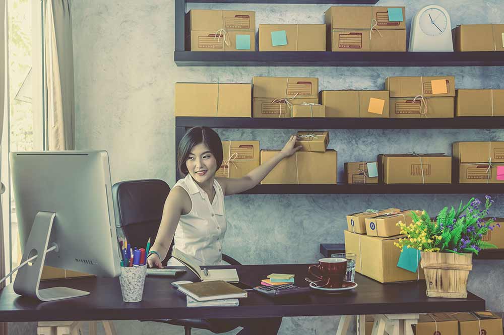 Woman sitting at a desk surrounded by packages