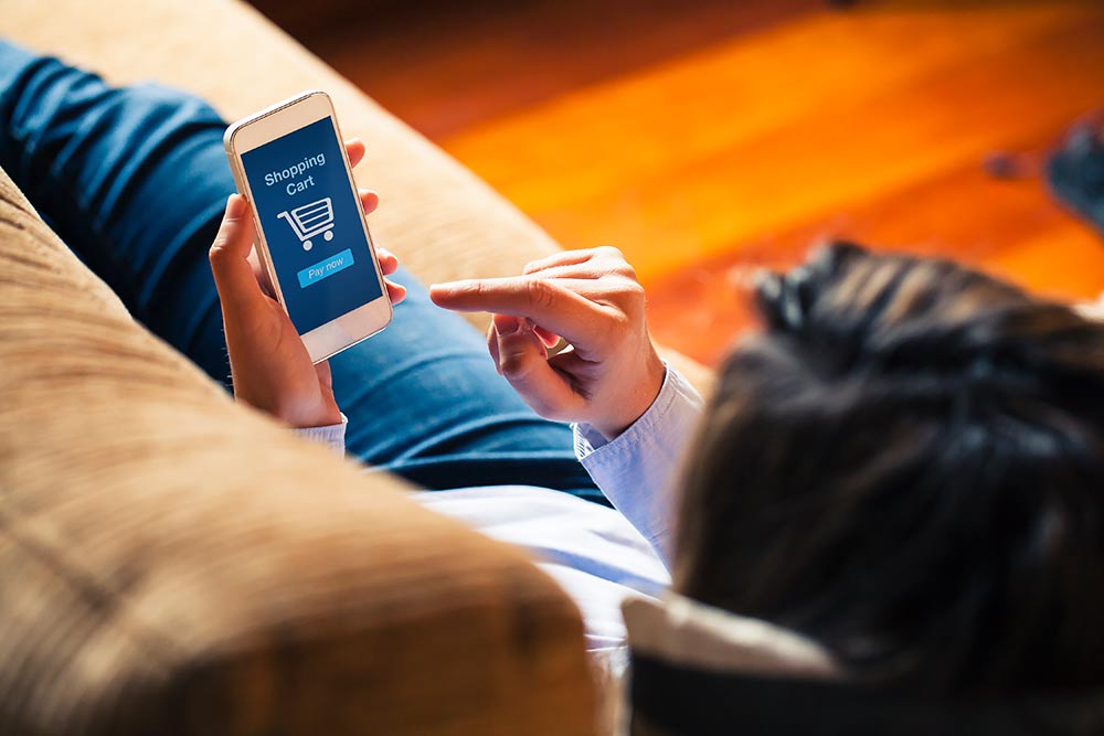 woman on couch completing purchase on phone