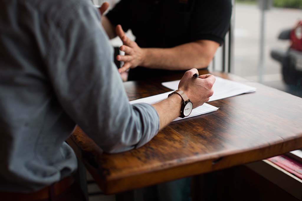 2 men sitting facing each other at a desk - mentorship