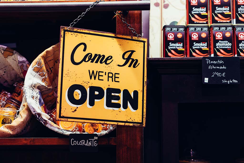 Open for business sign hangs in window of shop