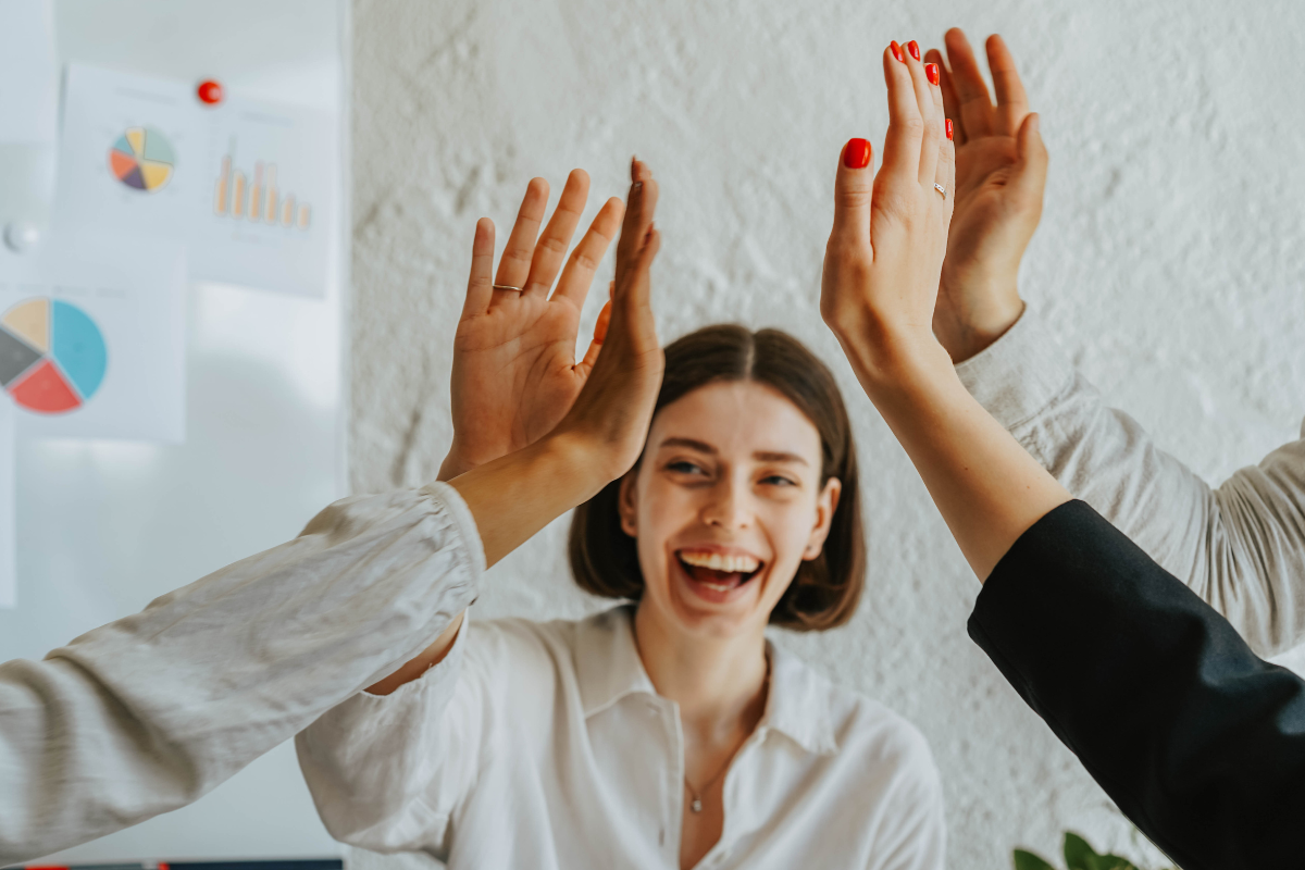 Young professionals celebrating 2021 FITT Education Awards with a high five