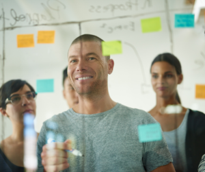 Preparing an international business plan - man drawing on a white board as his colleagues watch